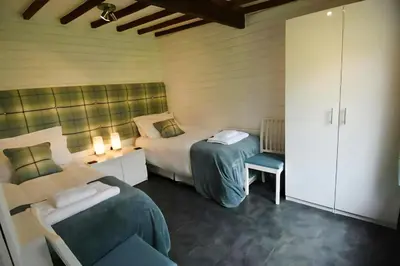 a bedroom with two beds and a chair in it at Mountain Lodge, Lake View, National Park in Borrowdale Valley
