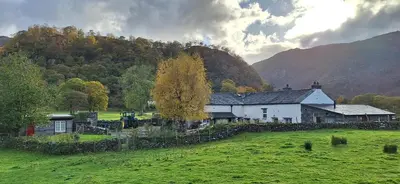 a house in the middle of a field with a hill at Mountain Lodge, Lake View, National Park in Borrowdale Valley