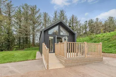 a black tiny house with a wooden deck at 2 Bed in Mouswald oc-b33444 in Mouswald