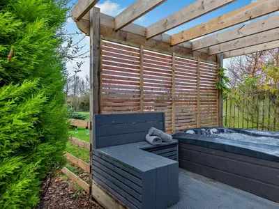 a hot tub in a garden with a wooden pergola at 1 Bed in Dearham 96373 in Dearham