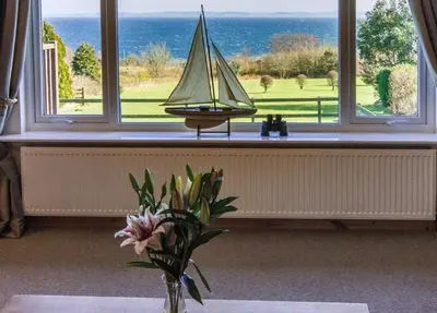 a vase with a sail boat on a window sill at Spacious holiday home with stunning sea views in Whiting Bay