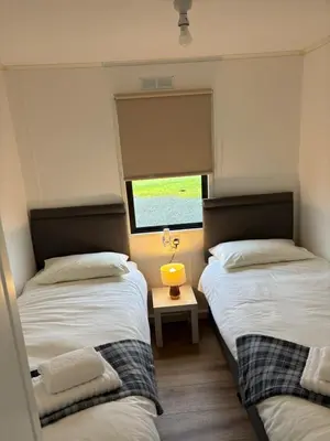 two beds in a small room with a window at Amazing Sunsets and Sea Views - Lodge Cabin Farm Stay - Caol Ila - Lodge 8 in Stranraer