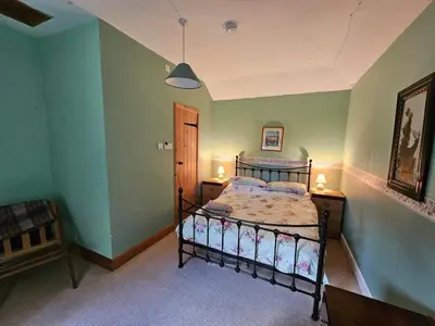 a bedroom with a bed in a room with green walls at Morton Mains Cottage