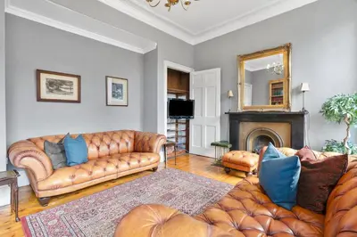a living room with two leather couches and a fireplace at Charming Central Stay in Moffat