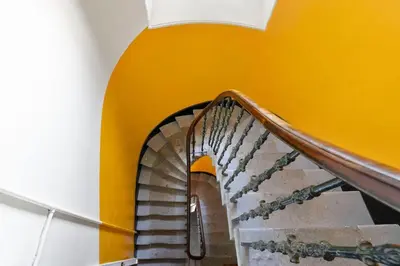 a spiral staircase in a building with an orange wall at Charming Central Stay in Moffat
