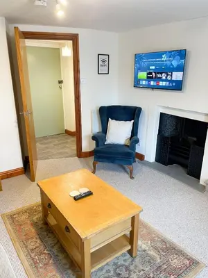 a living room with a blue chair and a coffee table at Hadrians Retreat, Cosy 1 Bed Flat - near M6 Jct45, A75, Gretna & Carlisle in Longtown