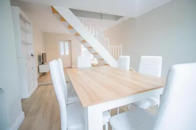 a dining room with a wooden table and white chairs at Your Perfect Home Away From Home in Workington