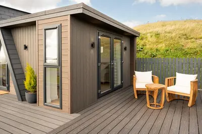 a cabin on a deck with two chairs and a table at Ardwall in Carsluith