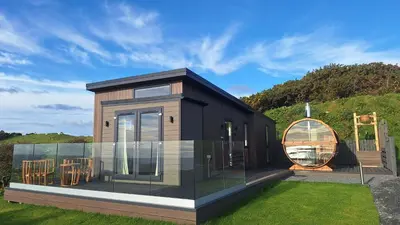 a black house with a large window and a yard at Barlocco in Carsluith