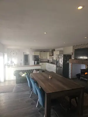 a kitchen and living room with a wooden table and blue chairs at Sandylands in Braystones