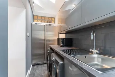 a kitchen with a sink and a stainless steel refrigerator at Faulkner Luxury Suites in Moffat
