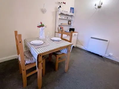 a dining room table and chairs with a table and a vase with flowers at Pass the Keys Cosy Romantic Getaway with Hot Tub in Whithorn