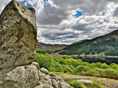 a large rock sitting on the side of a lake at Pass the Keys Cosy Romantic Getaway with Hot Tub in Whithorn