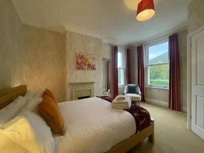a bedroom with a large bed and a fireplace at Sunnycroft - Hot tub hire available, fitness centre, free parking in Keswick