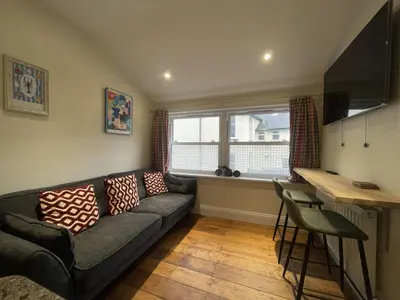 a living room with a couch and a table at Sunnycroft - Hot tub hire available, fitness centre, free parking in Keswick