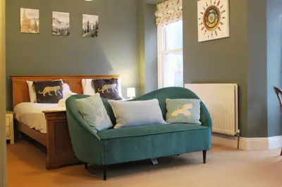 a bedroom with a bed and a green couch and a chair at Sunnycroft - Hot tub hire available, fitness centre, free parking in Keswick