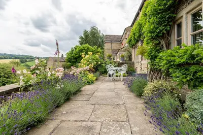 a garden with purple flowers next to a house at Woodlea Cottage in Moffat