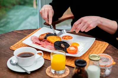 a person eating a breakfast plate of food on a table at Victorian House in Grasmere