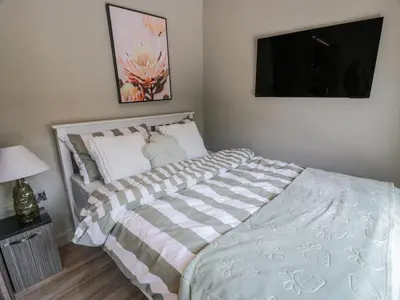 a bedroom with a bed and a tv on the wall at Cabin At The Brig in Annan