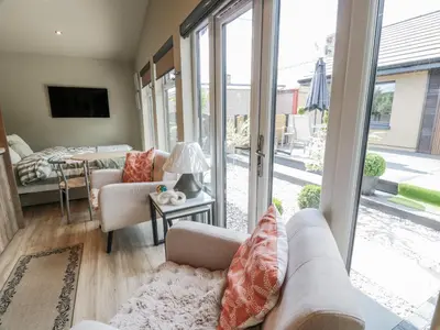 a living room with a couch and a tv and sliding glass doors at Cabin At The Brig in Annan