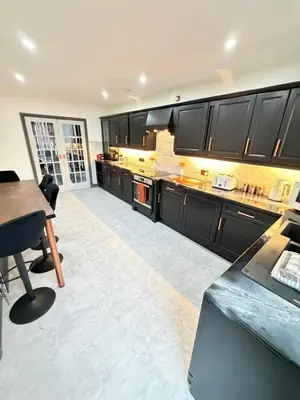 a large kitchen with black cabinets and a table at Seaside Retreat in Harrington