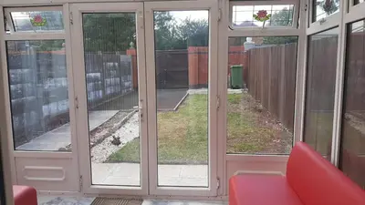 a room with glass doors and a red chair at 3 Bedroom Cozy House-Short and Long Stay in Moffat