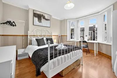 a bedroom with a white bed and some windows at Spacious 5BR Home in Cardiff Bay with Office Area in Moffat