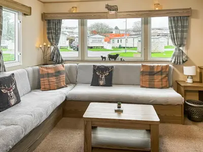 a living room with a couch and a large window at Kjs Holiday Haven in Ayr