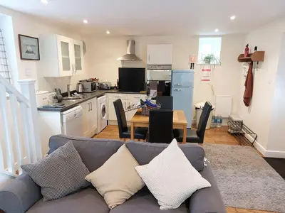 a living room with a couch and a kitchen at The Coach House- Canonbie in Canonbie