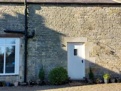 a building with a white door and a brick wall at The Coach House- Canonbie in Canonbie