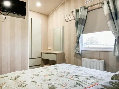 a bedroom with a bed and a window and a mirror at H And D Greenan Village in Ayr