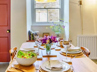 a wooden table with a bowl of salad and wine glasses at 2 Bed in Eaglesfield 85288 in Eaglesfield