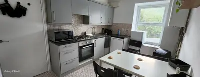 a kitchen with white cabinets and a table and a window at The Spacious Urban Retreat in Douglas