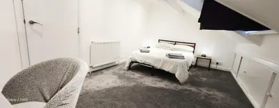 a white bedroom with a bed and a chair at The Spacious Urban Retreat in Douglas