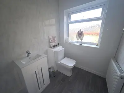 a bathroom with a toilet and a sink and a window at Mid Street Retreat, Steps from the Beach, Whitehaven in Whitehaven