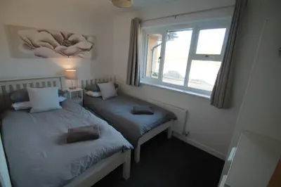 two twin beds in a room with a window at Beach Stroll Retreat, Swanage, Dorset in Moffat