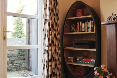 a book shelf with a mirror next to a window at Azalea in Keswick