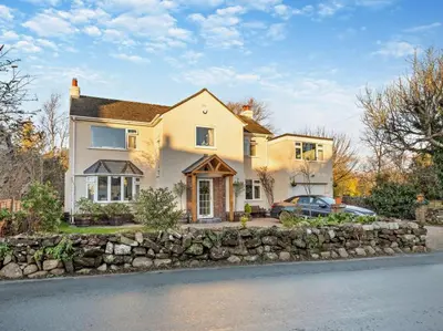 a large white house with a stone wall at Blengfell by Prestige Properties SA in Gosforth