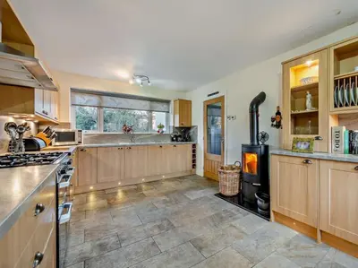 a large kitchen with wooden cabinets and a stove at Blengfell by Prestige Properties SA in Gosforth