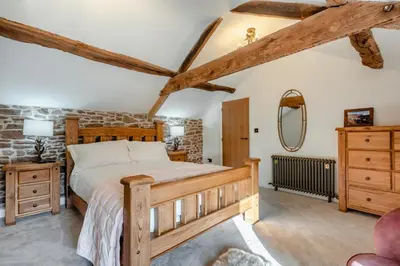 a bedroom with a wooden bed and a stone wall at 3 Bed in Wigton oc-f33746 in Westward