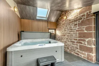 a bathroom with a bath tub in a brick wall at 3 Bed in Wigton oc-f33746 in Westward