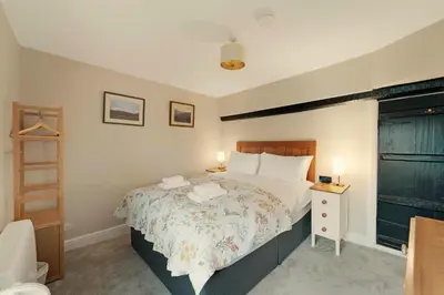 a bedroom with a large bed with a wooden headboard at Walthwaite How Cottage in Chapel Stile