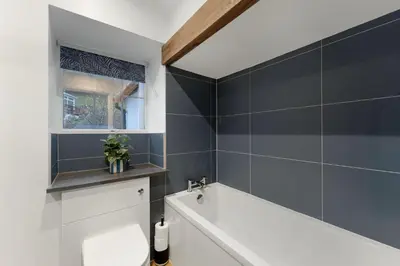 a bathroom with a bath tub and a window at Walthwaite How Cottage in Chapel Stile