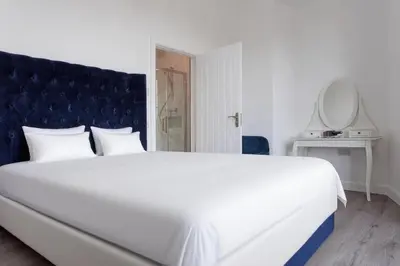 a bedroom with a large white bed with a blue headboard at Savoy 5 in Ayr