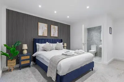 a bedroom with a blue and white bed and a bathroom at Stone Street Modern 3-Bed for Groups & Families in Broughton