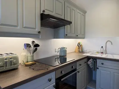 a kitchen with white cabinets and a counter top at The Cottage in Keswick