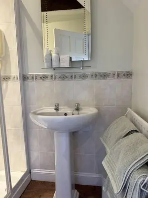 a bathroom with a white sink and a mirror at The Cottage in Keswick