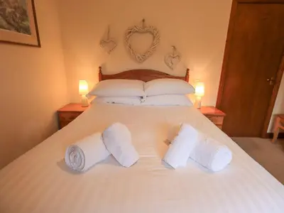 a bedroom with a large white bed with two towels at Thrang View in Ambleside
