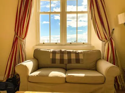 a couch in a living room with a window at Moir Cottage in Portpatrick