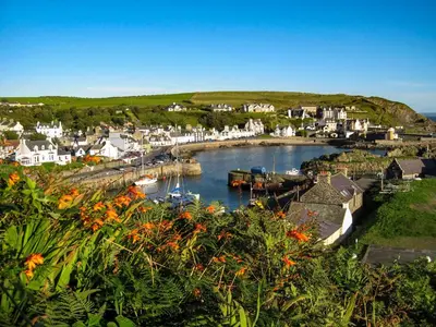 a town with a harbor with boats in the water at Moir Cottage in Portpatrick